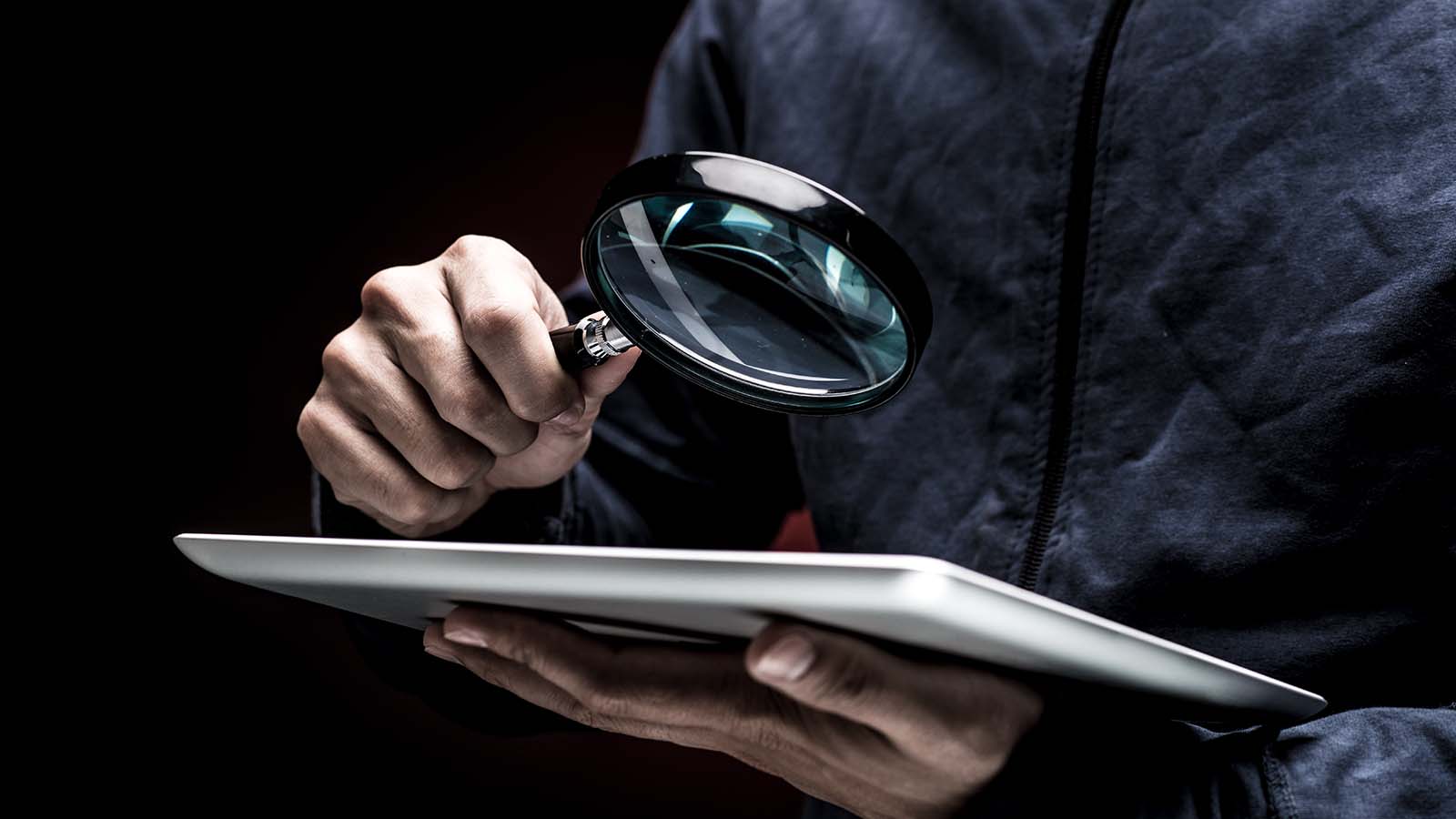 quelqu'un examinant un smartphone à l'aide d'une loupe