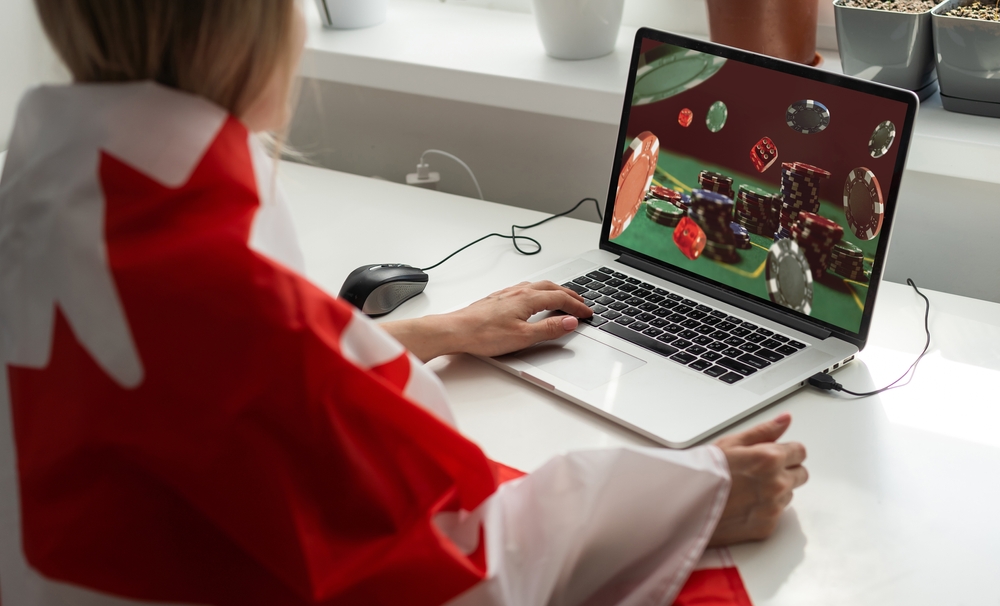 A woman enjoys playing at an online casino, wrapped in the Canadian flag.