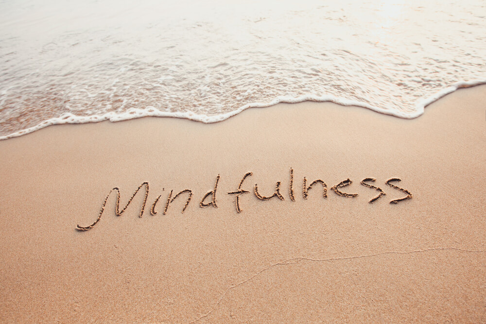 Mindfulness etched in sand along the beach
